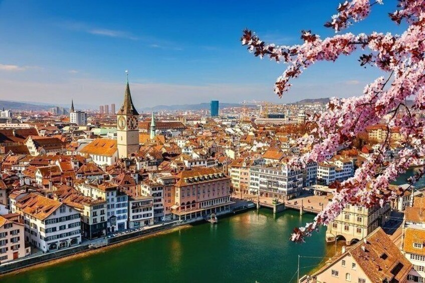Eine Stadtlandschaft mit einem markanten Turm, einem Fluss und Kirschblüten. 1