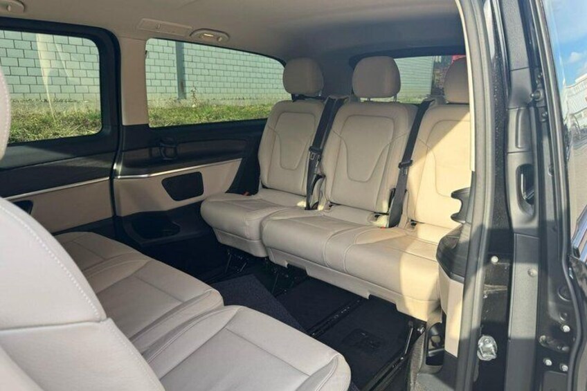 Ein Auto Innenraum mit beigen Ledersitzen, einer Mittelkonsole und einem Rückspiegel. 2