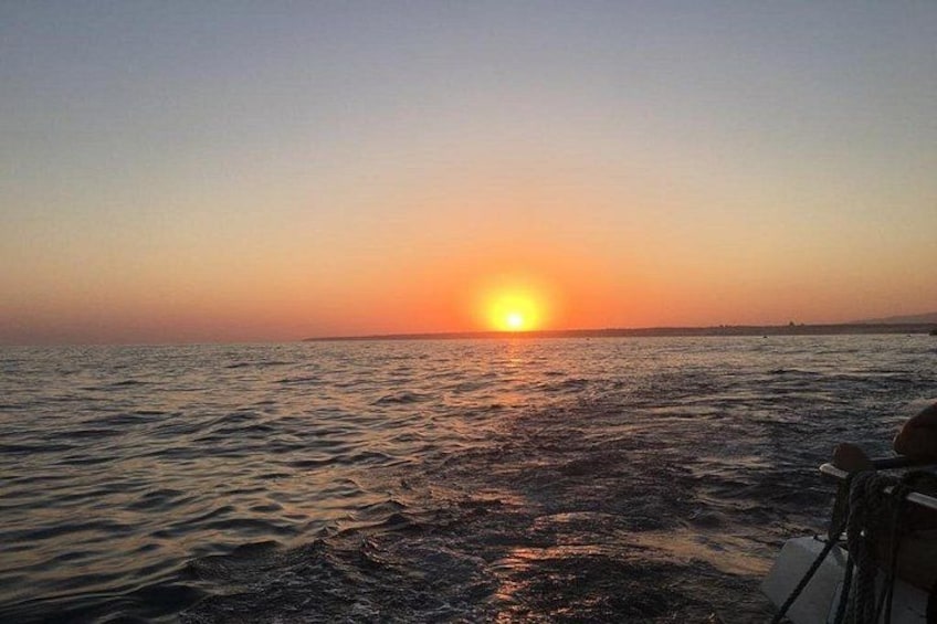 A sunset over a body of water with a boat in the foreground. 3