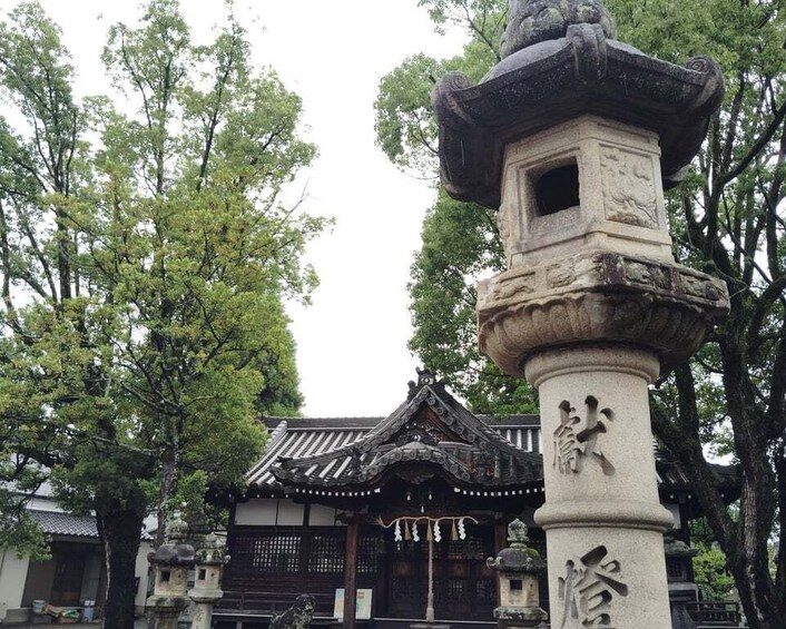A traditional Japanese torii gate with a stone lantern in front, surrounded by trees and a traditional building in the background. 3