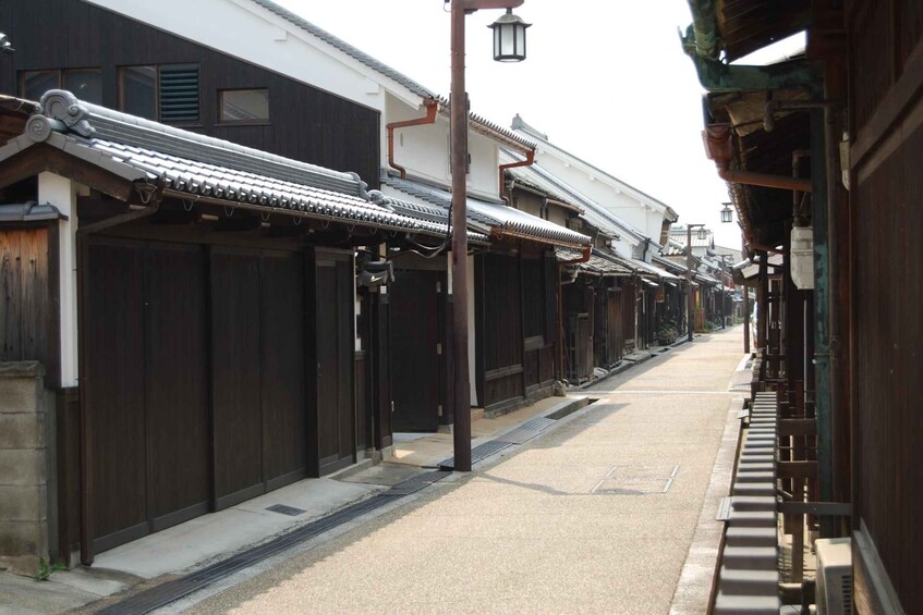 A narrow street lined with traditional wooden buildings, a clear sky, and a street lamp. 5