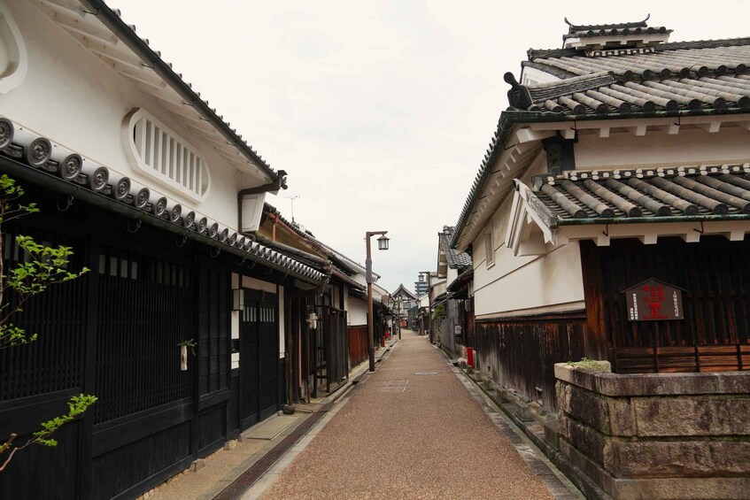 A narrow alley flanked by traditional buildings with tiled roofs and wooden fences. 2