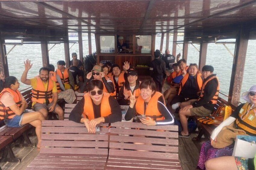 People on a boat wearing life jackets, seated on wooden benches. 4