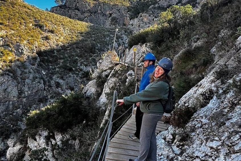A wooden boardwalk with hikers wearing helmets and backpacks. 3