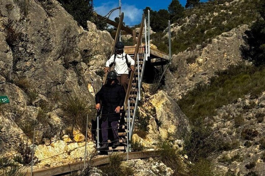 A person climbing a wooden ladder on a rocky hillside. 4