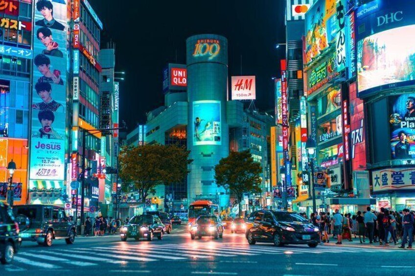 A busy urban street at night with illuminated billboards and vehicles. 4