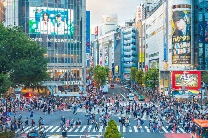 A busy urban street with pedestrians crossing, commercial buildings, and billboards. 3
