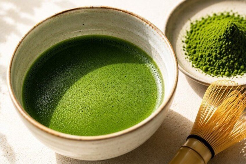 A bowl of green tea, a whisk, and a pile of green powder. 1