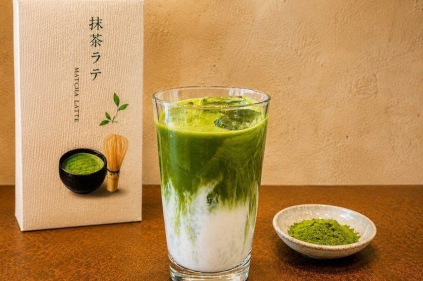 A matcha latte in a glass, a matcha powder bowl, and a matcha latte box. 1