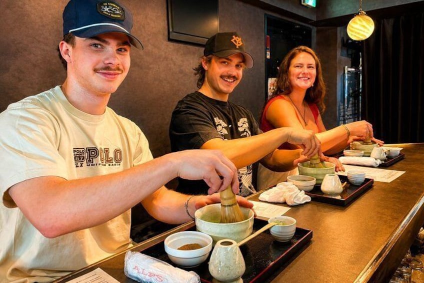 Three people preparing food at a counter with bowls and chopsticks. 3