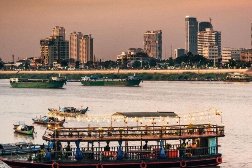A river with boats, a large floating structure, and a city skyline in the background. 2
