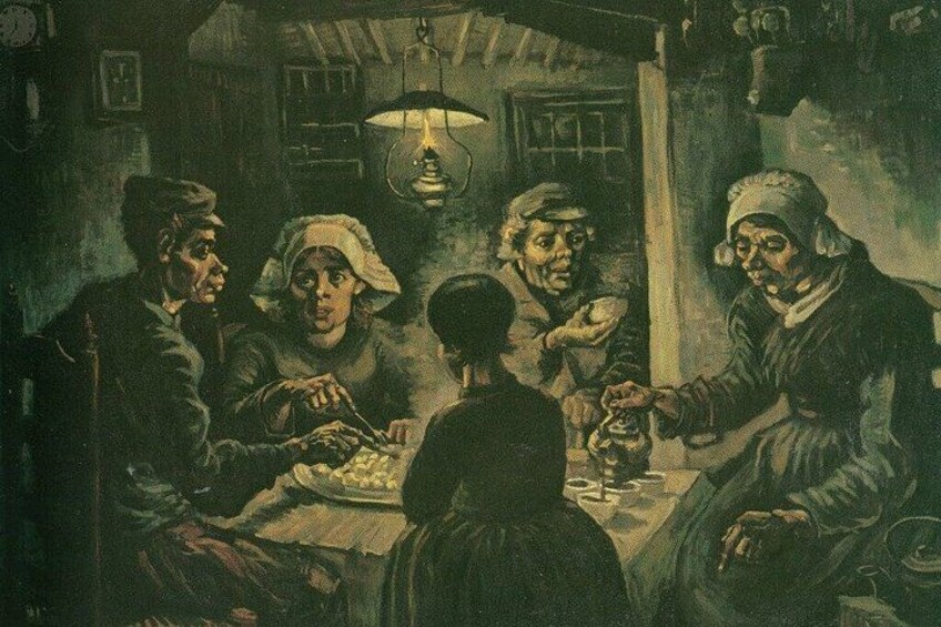 A group of people sitting around a table in a dimly lit room with a hanging light fixture. 2