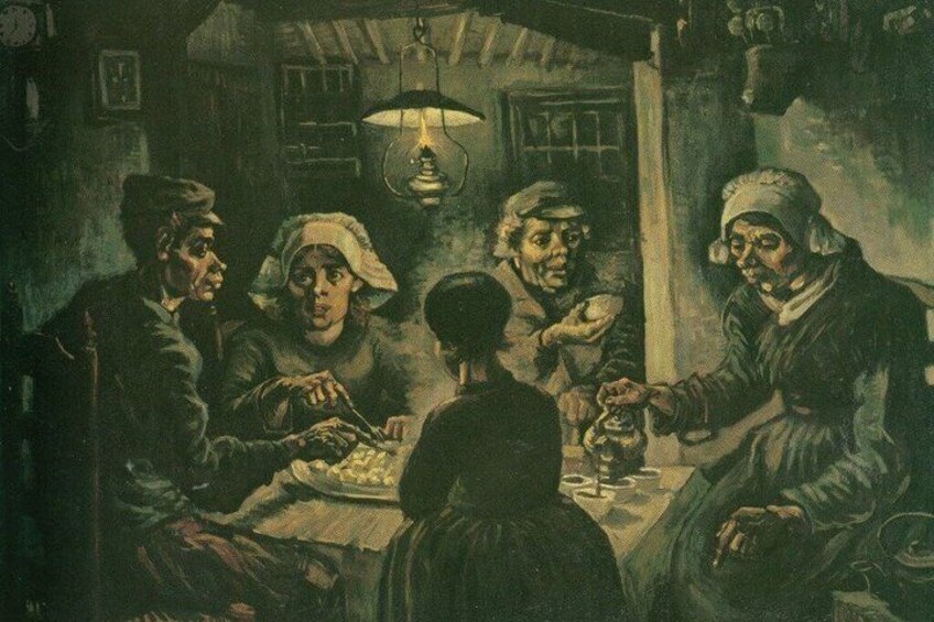 A group of people sitting around a table in a dimly lit room with a hanging light fixture. 2