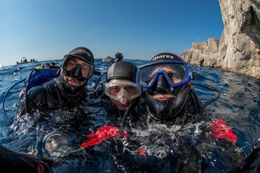 Tre personer som snorklar i klart, blått vatten med klippiga branter i bakgrunden. 2