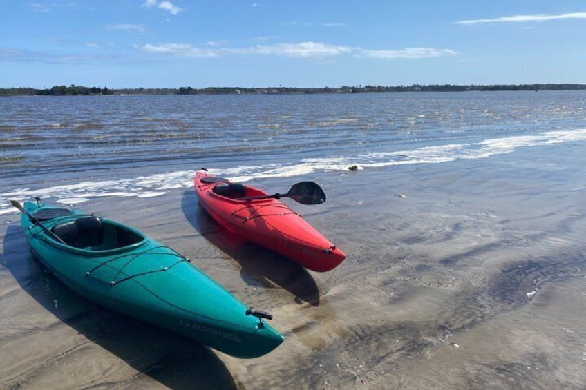 Two kayaks on a sandy beach with water in the background. 4