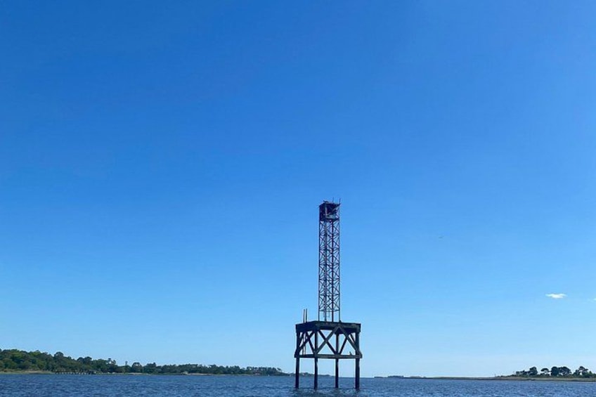A tall metal structure with a platform, surrounded by water and a clear sky. 5