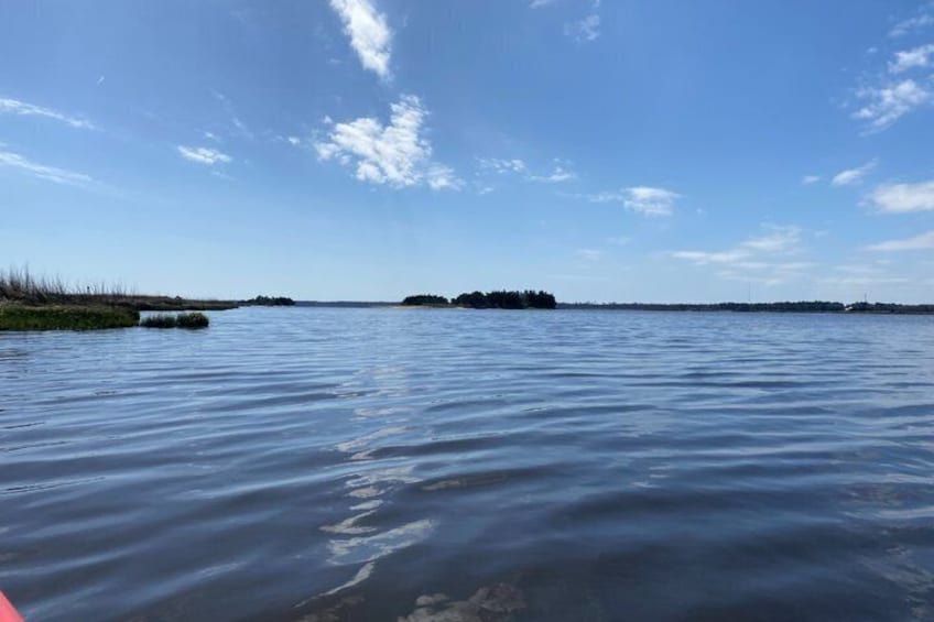 A calm lake with a clear sky, distant land, and a small island. 2