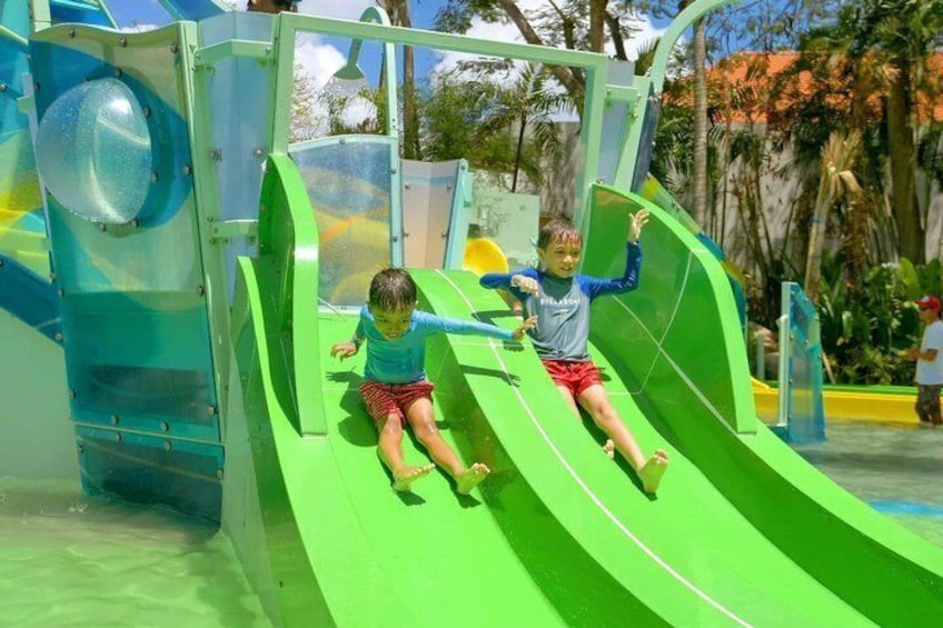 Dos niños se deslizan por un tobogán acuático verde en un parque acuático. 5