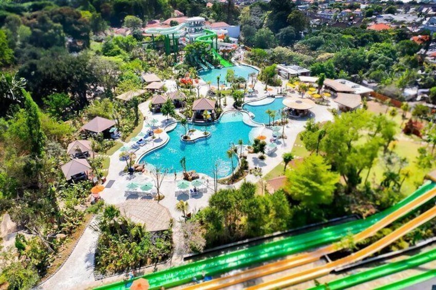Un resort con varias piscinas, palmeras y un tobogán verde. 1