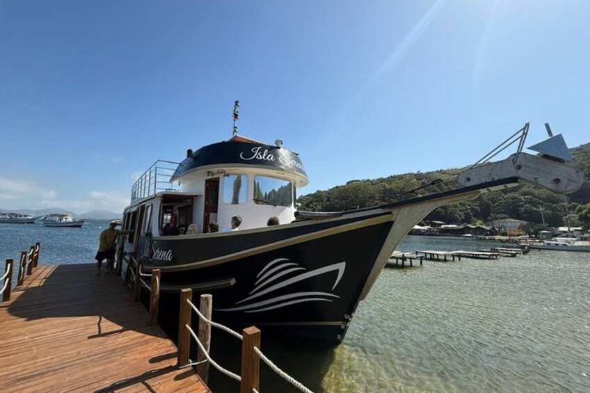 A boat docked at a pier with a clear sky and a hilly landscape in the background. 3