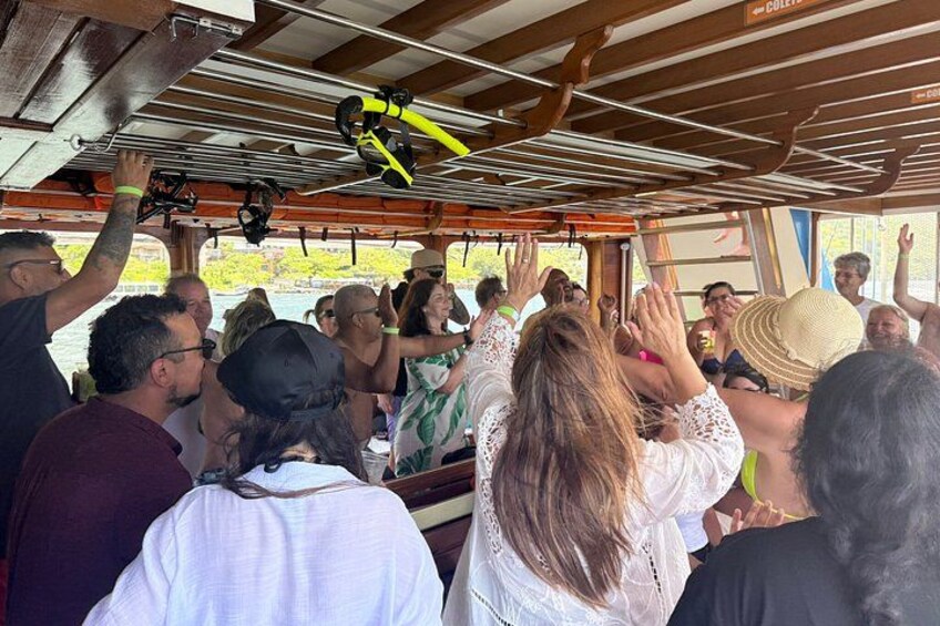 A group of people on a boat, some holding onto the railing, with a yellow kayak visible above. 4