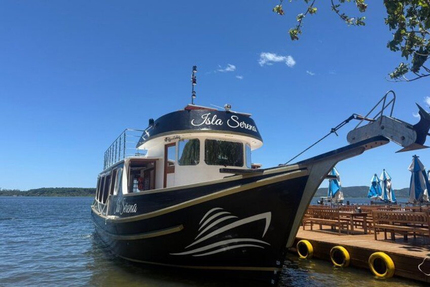 A boat named 'Isla Sereno' docked at a pier with a clear blue sky and calm water. 2
