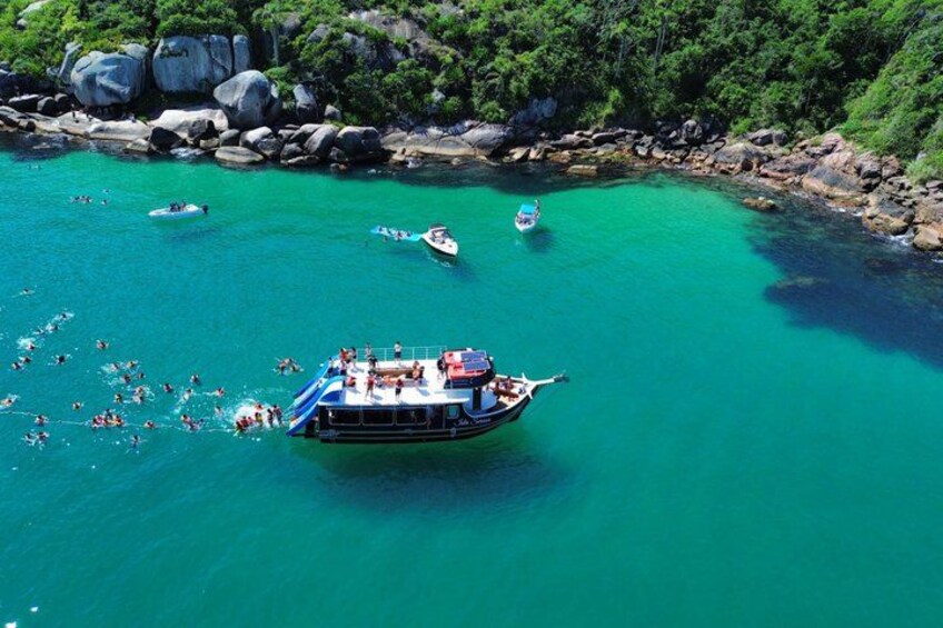 A boat with people on a turquoise water body surrounded by rocks and greenery. 1