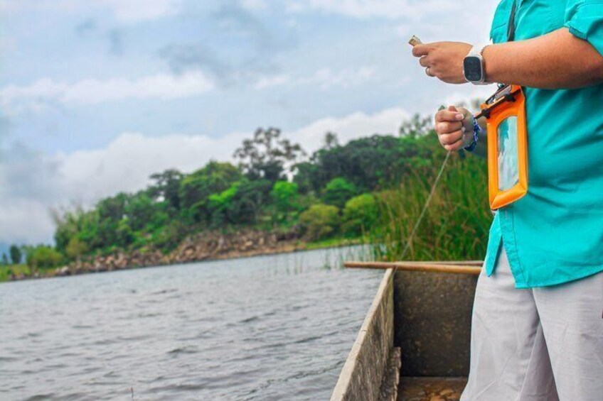 A person fishing by a calm river with lush greenery in the background. 3