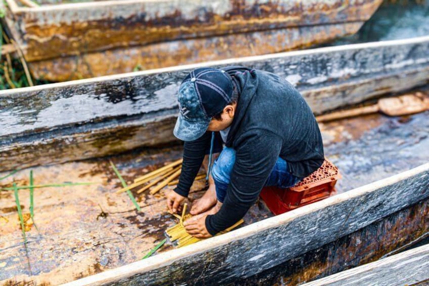 A person working on a wooden boat in a river. 2