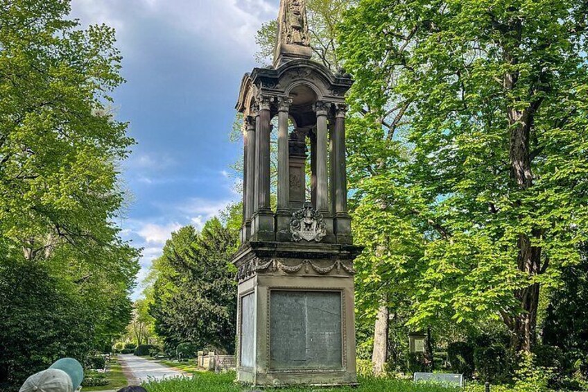 A classical monument with columns and a statue, surrounded by lush greenery and trees. 2