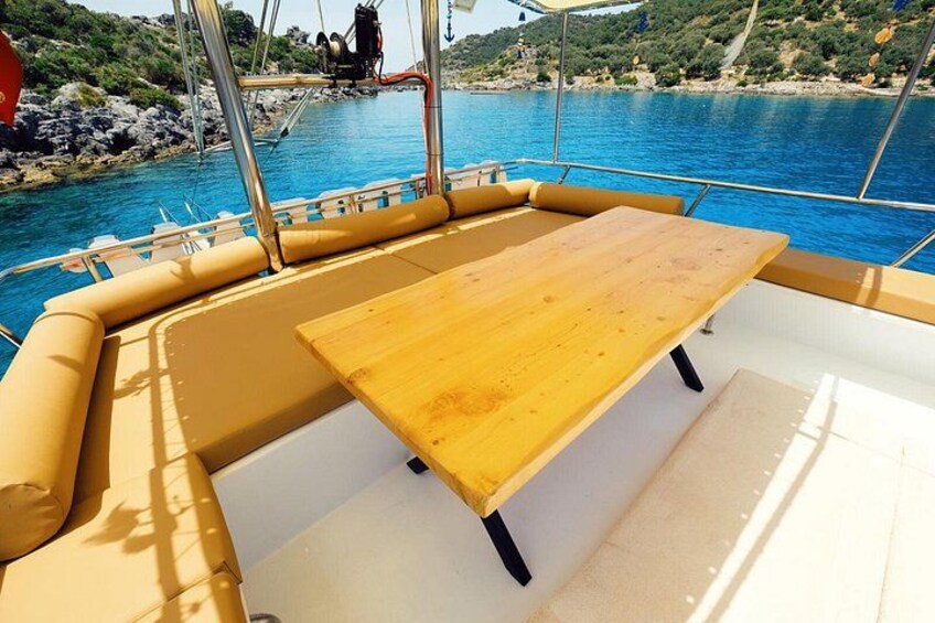 A boat's deck with a wooden table and yellow cushions. 4