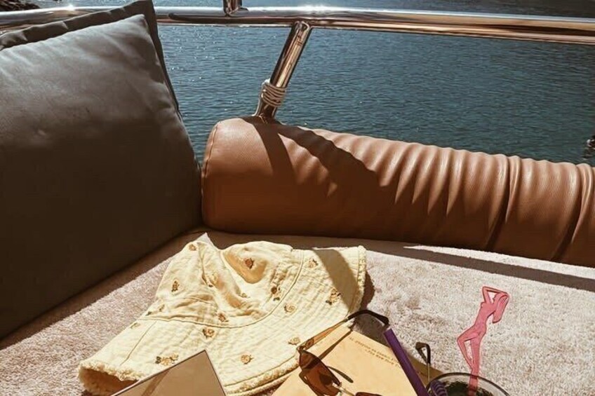 A boat interior with a cushioned seat, a folded garment, and a pair of sunglasses. 2