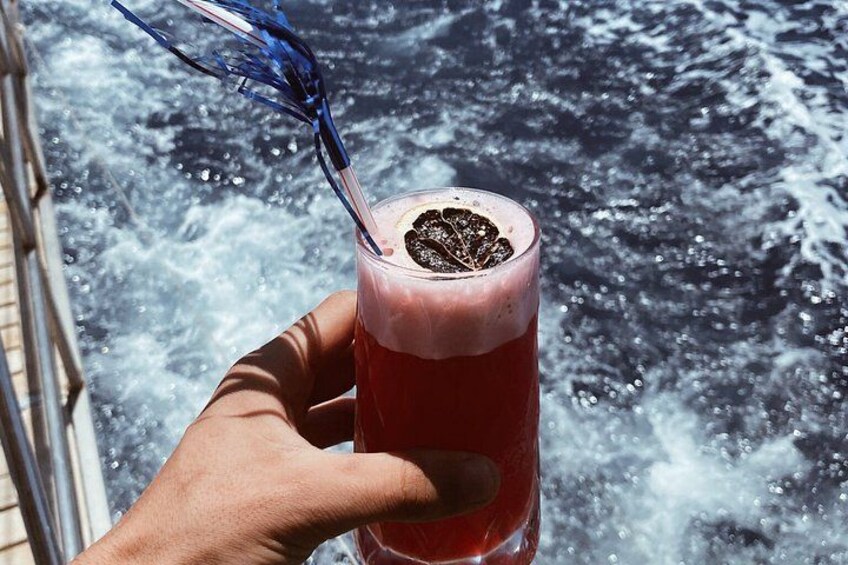 A hand holding a glass with a red beverage and a blue straw, with water splashing in the background. 5