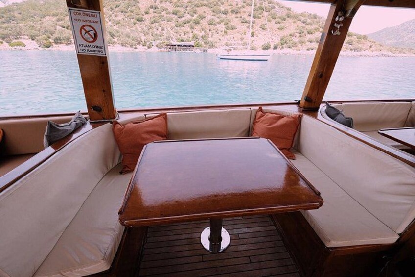 A boat interior with a wooden table and cushioned seating. 2