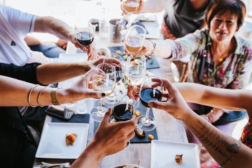 Un grupo de personas brindando con copas de vino alrededor de una mesa. 1