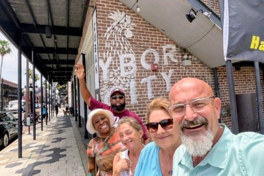 A group of people posing in front of a building with a large sign that reads 'YBOR CITY.' 1