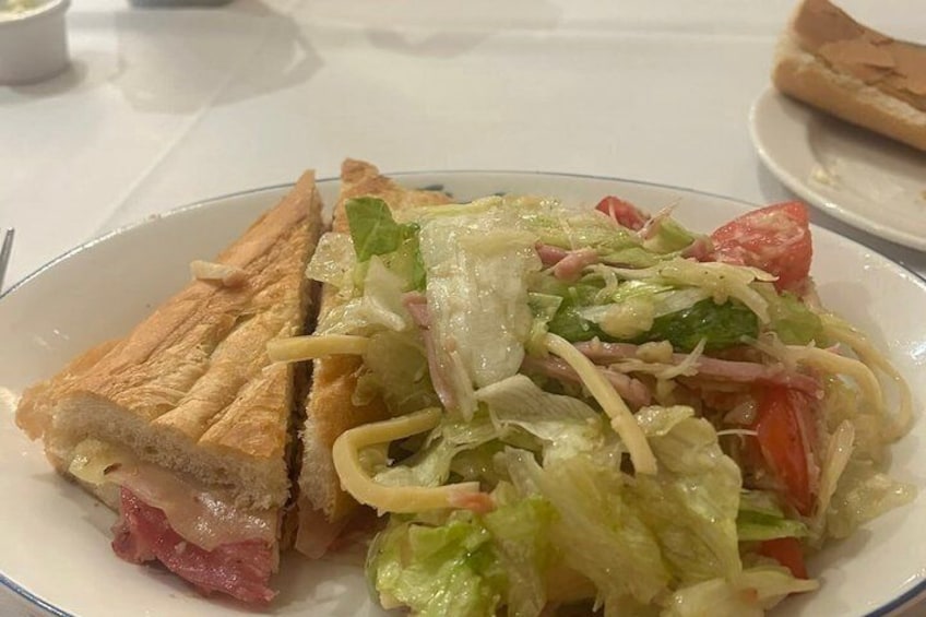 A sandwich with lettuce, tomatoes, and ham on a white plate. 3