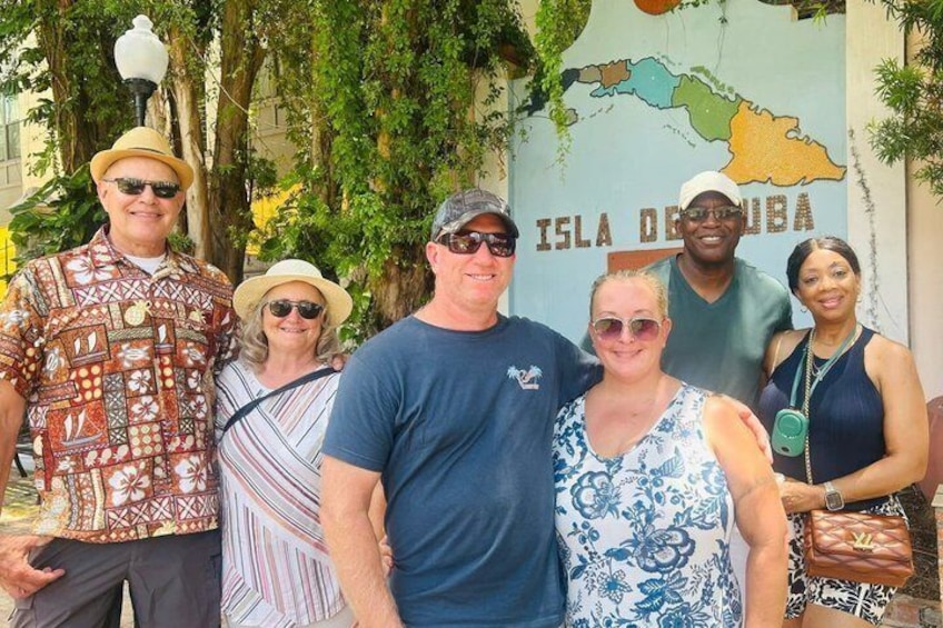 A group of people standing in front of a map of the Island of Cuba. 2