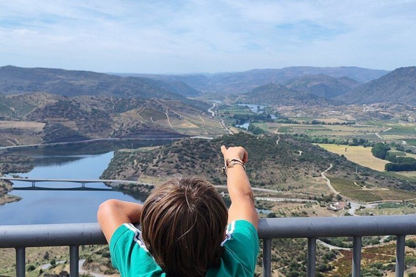 A person overlooking a valley with a river, hills, and a bridge. 5