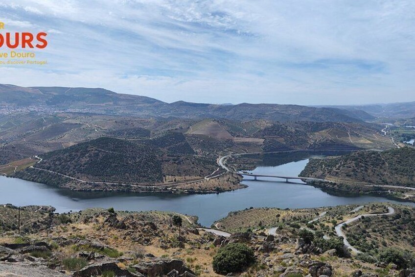 A mountainous landscape with a river, a bridge, and a winding road. 1