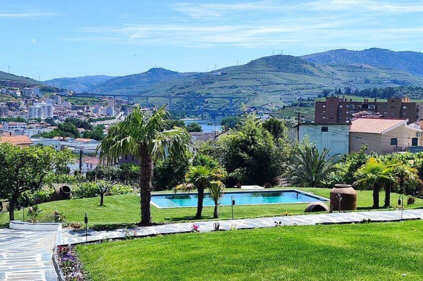 A swimming pool surrounded by greenery, a cityscape in the background, and hills. 2