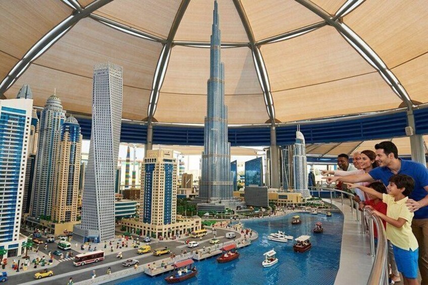A model cityscape with a prominent skyscraper, a waterfront with boats, and a dome structure. 1