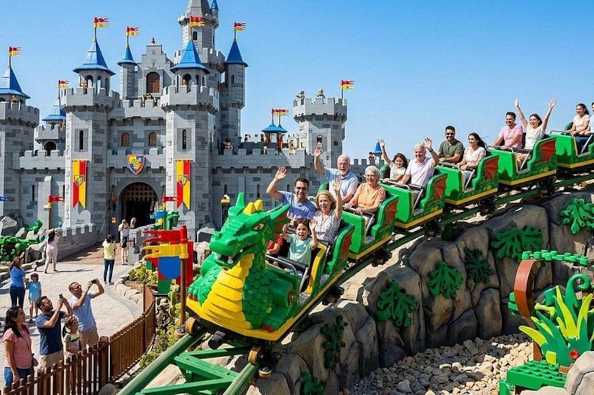 A dragon-themed roller coaster at a theme park with a castle backdrop. 3