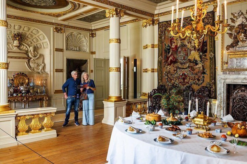 An opulent room with a banquet table set for a meal, ornate decorations, and a large tapestry. 5