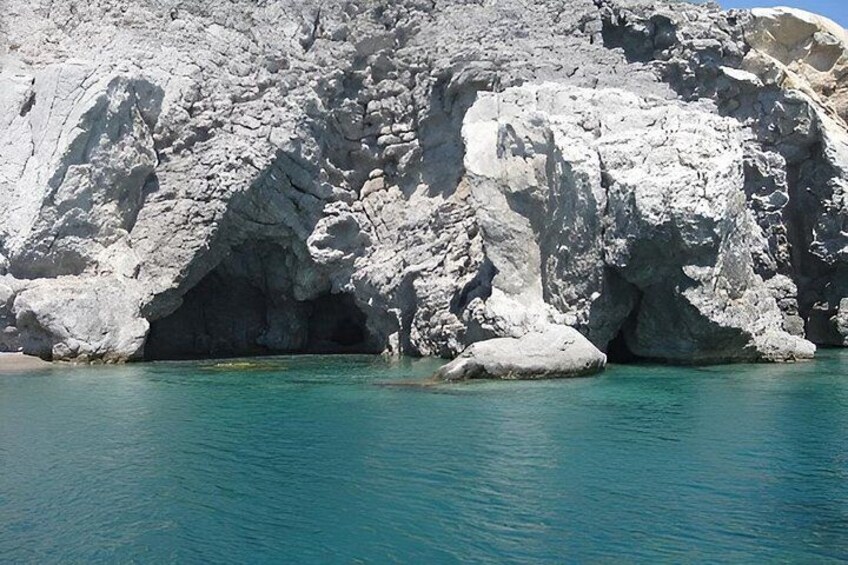 A rocky coastline with clear turquoise water and a large cave entrance. 3