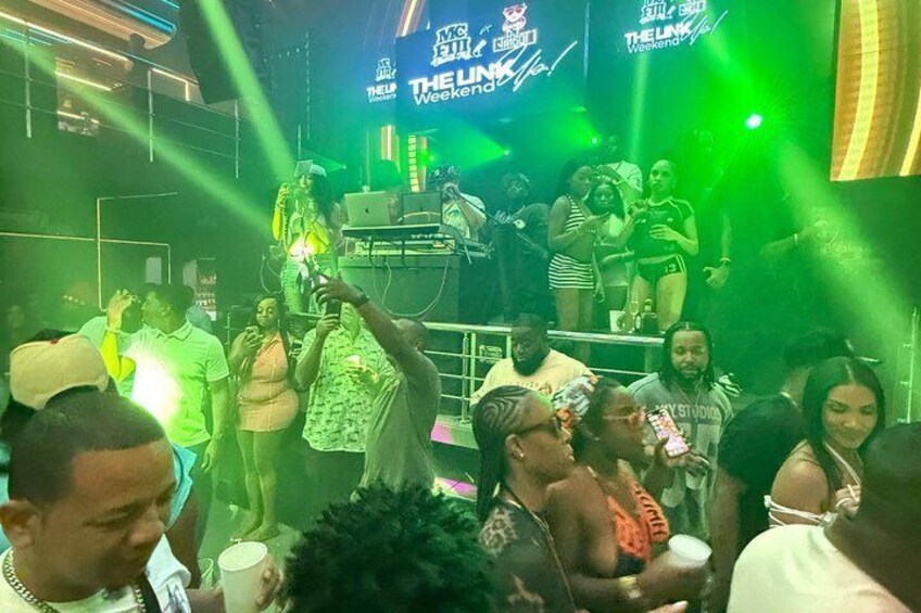 A nightclub with a stage, DJ booth, and people dancing. 4