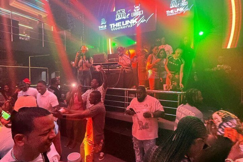 A crowded indoor event with a DJ booth and stage lighting. 2