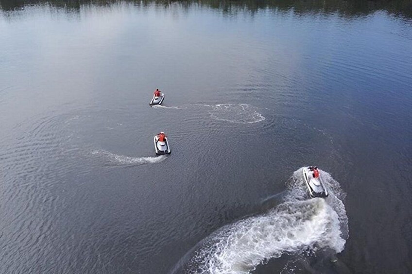 Three jet skis on a calm lake with clear reflections. 3