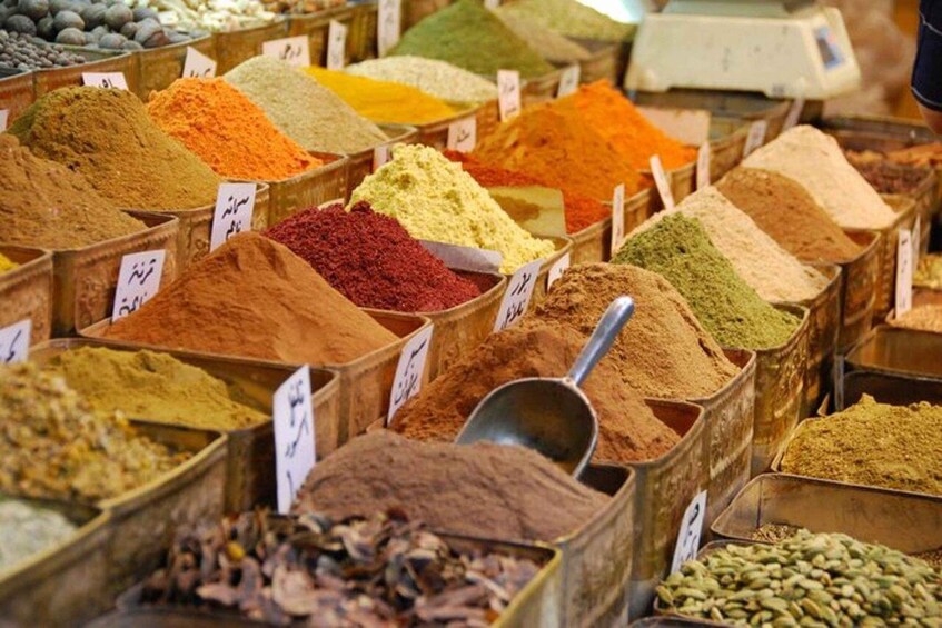 A variety of spices displayed in wooden bins with price tags. 4