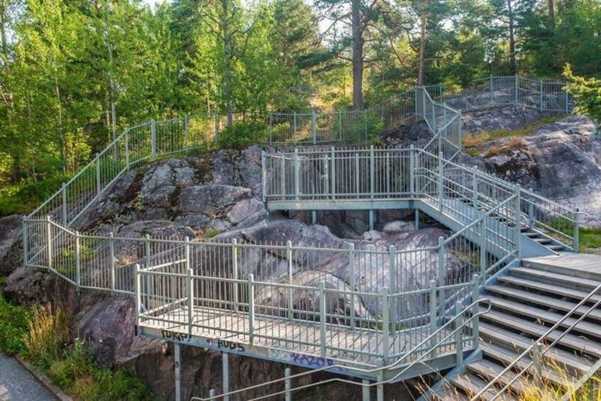 A metal staircase leading up to a platform surrounded by rocks and trees. 4